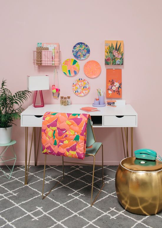 a bright feminine home office with a blush wall, a bright gallery wall, a colorful chair and gold touches