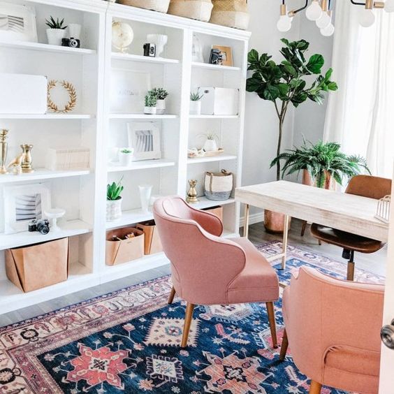 a bright girlish home office with a wooden desk, pink chairs, an open storage unit and a bright printed rug