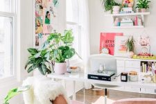 a bright home office with blush chairs, a colorful gallery wall, bright artworks and books and lots of greenery
