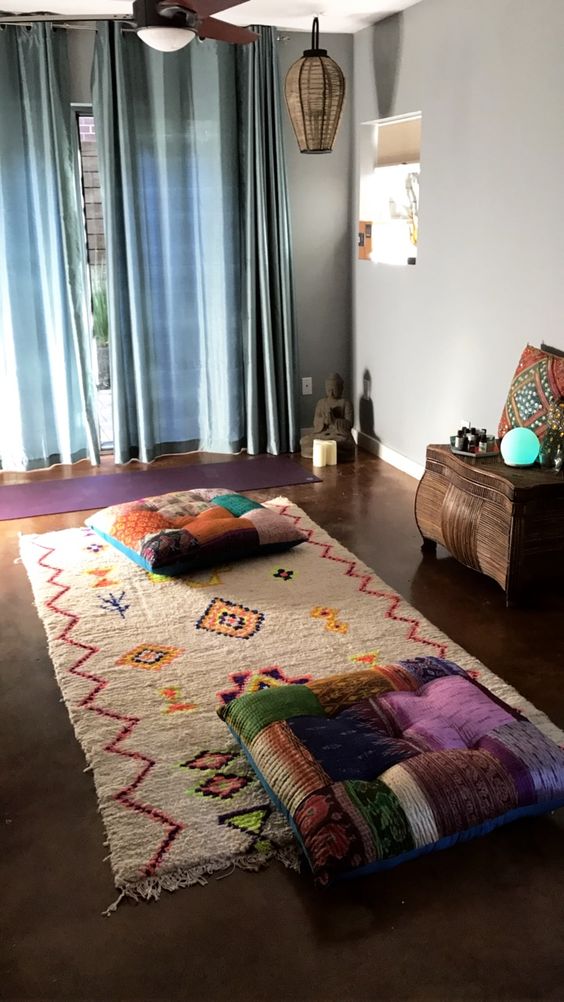 a colorful and boho meditation space with pillows, a colorful rug and wicker lamps