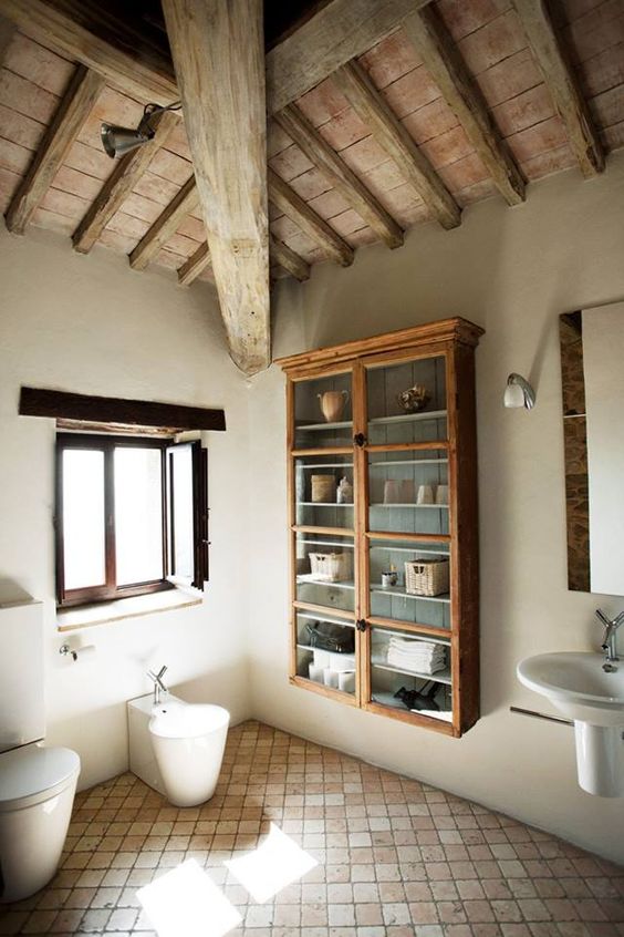 A contemporary barn bathroom with a wooden ceiling with beams, a wall mounted dresser, a tile floor and modern appliances