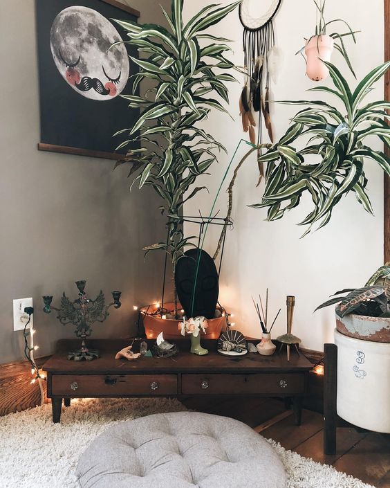a cozy boho meditation space with low furniture, a rug, an ottoman, potted greenery and boho decor