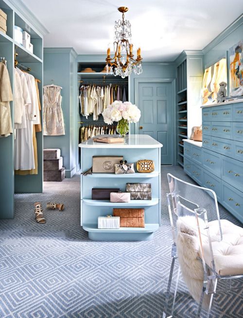 a dreamy blue vintage closet with open and closed storage units, drawers, cabinets, a gold crystal chandelier and a clear chair