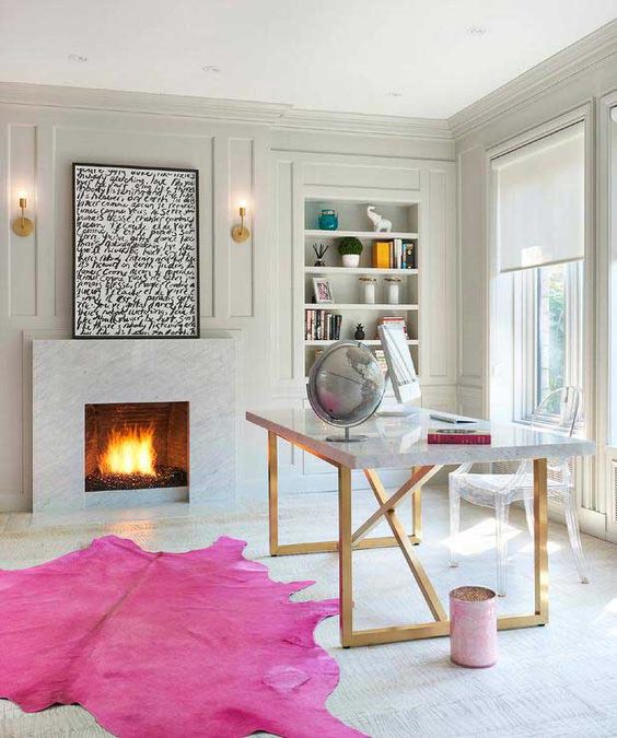 a glam home office with a fireplace, a desk, a hot pink rug and some comfy furniture