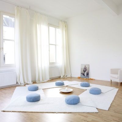 a home meditation room with white rugs and blue cushions and much light and air
