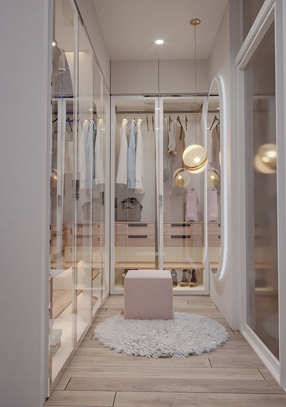 a lovely contemporary girlish closet a lit up wardrobe and glass doors and small cabinets with drawers built inside and a pink pouf