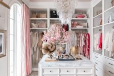 a lovely glam girlish closet with open storage units, drawers, a large cabient with drawers for accessories, a crystal chandelier, a printed rug