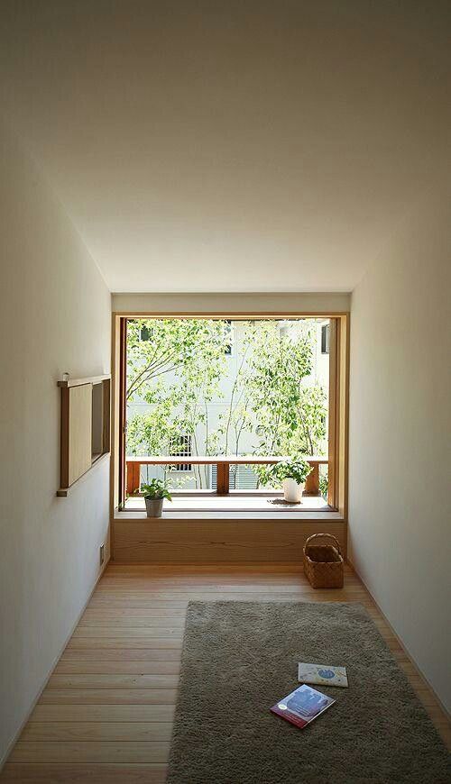 a minimalist meditation space with a rug, some potted greenery, baskets and a window with greenery
