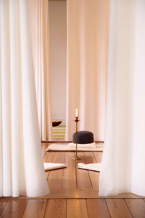 a minimalist meditation space with curtains, rugs, pillows and candles in candle holders