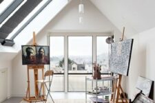 a modern artist home studio with skylights and windows, a couple of easels, a cart and a stool is great for creating