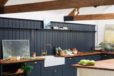 a modern barn kitchen with wooden beams, graphite grey shaker style cabinets, butcherblock countertops, a white kitchen island