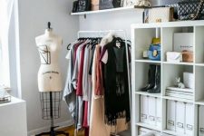 a pretty neutral closet with a makeshirt part, open storage shelves, a tufted bench, hats as decor and a printed rug is amazing