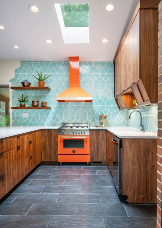 A rich stained modern kitchen with white countertops, a bold orange cooker and a hood and a bright blue geo tile backsplash