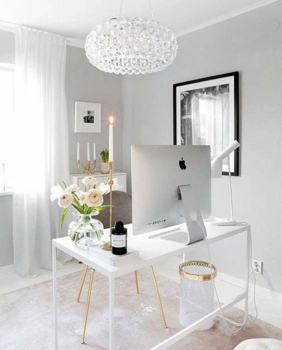 a sophisticated feminine home office with white and grey furniture, a crystal chandelier and touches of gold