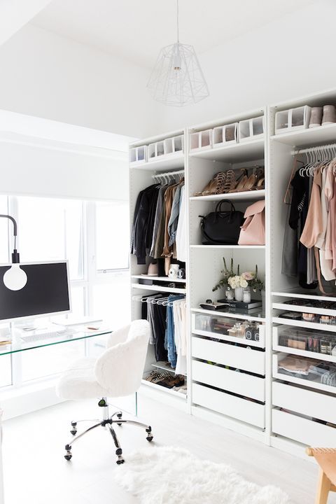 a stylish neutral feminine closet with an open storage wardrobe, drawers, a clear glass desk, a white chair and cool lamps