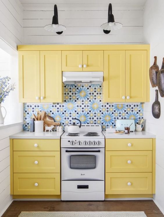 a tiny yellow kitchen with shaker cabinets, a bold blue patterned tile backsplash is a cheerful and fun space to be in