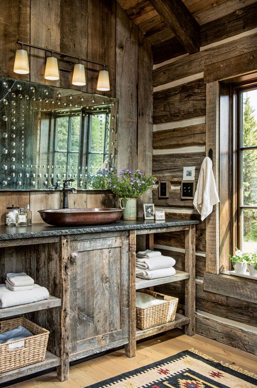 a vintage barn bathroom fully clad with reclaimed and weathered wood, with a catchy mirror, a chandelier and a wooden vanity