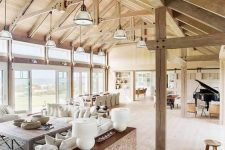 a welcoming barn living room with a stained wooden ceiling and beams and pillars, neutral seating furniture, wooden furniture items and a piano