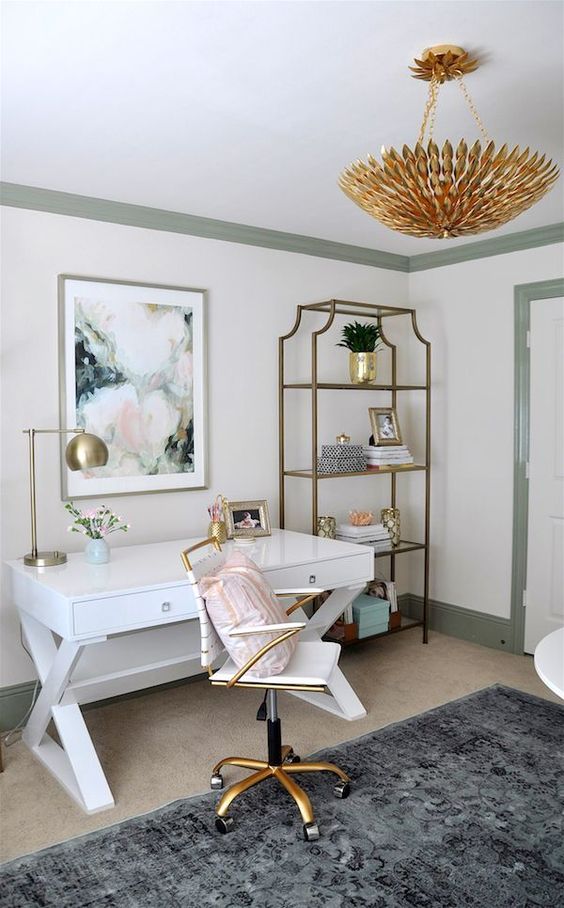an elegant feminine home office with a white desk, an open storage unit, a gold chandelier and a small chair