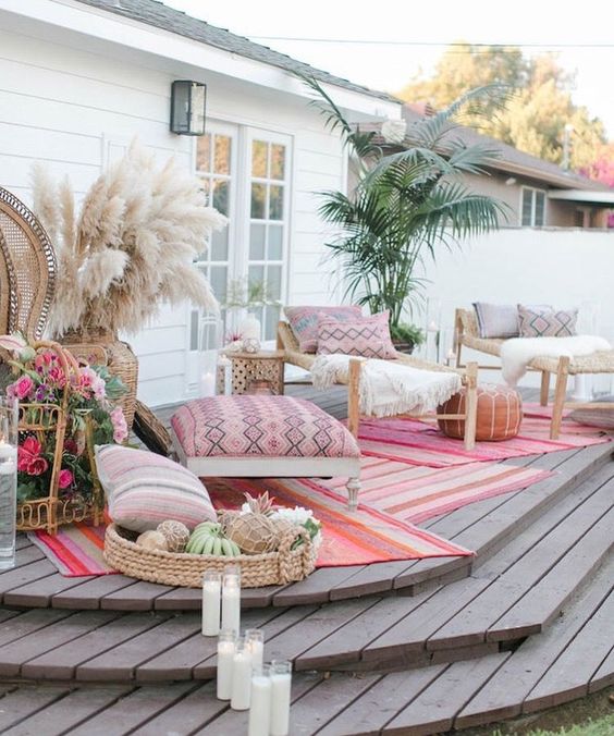 a boho deck with rattan furniture, pampas grass, greenery in a pot, candles and lots of floral arrangements