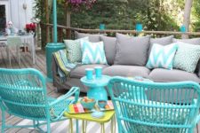 a bright deck with turquoise furniture, a grey sofa and printed pillows plus a printed rug for fun