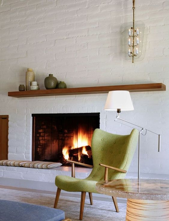 A chic mid century modern living room done with white brick walls and green accents