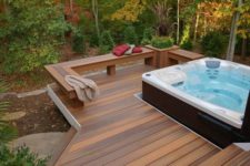 a contemporary deck with a built-in bench with a planter and a large jacuzzi plus a view to the forest
