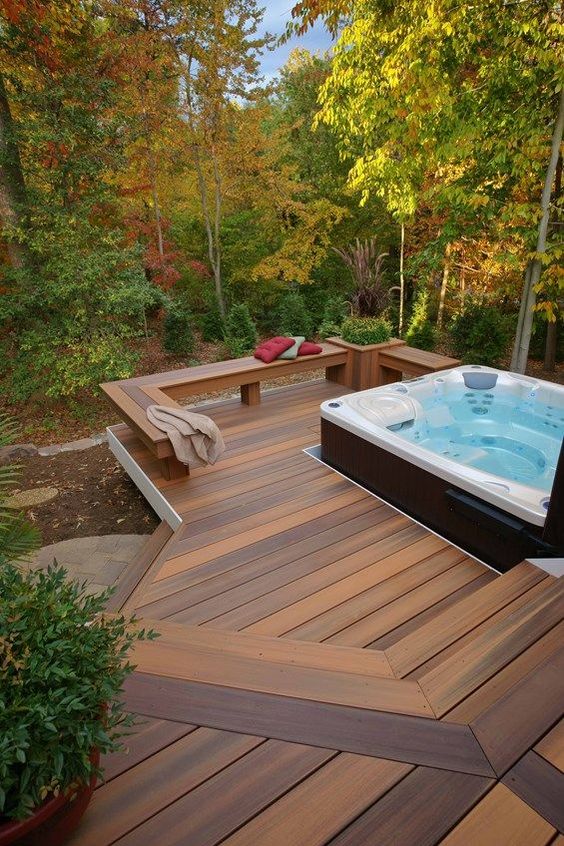 A contemporary deck with a built in bench with a planter and a large jacuzzi plus a view to the forest