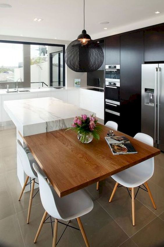 a contrasting kitchen island of white stone and a plywood table is a bold additional to monochromatic kitchen
