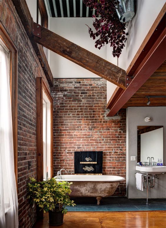 a creative bathroom with red brick walls, wooden beams and an antique bathtub and looks unique