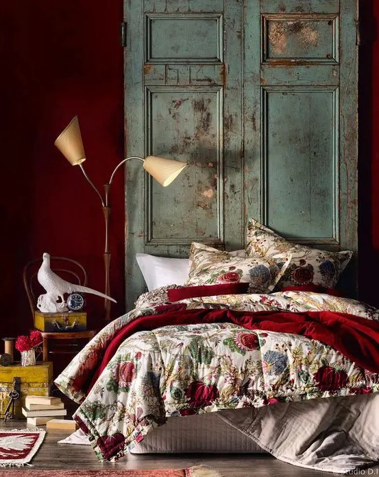 a deep red statement wall and a matching bedspread add color and interest to the room