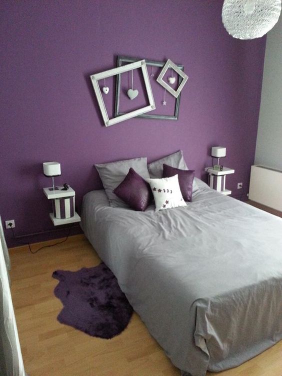 a fun contemporary bedroom with a purple accent wall, a bed, floating nightstands, picture frames and grey and purple bedding