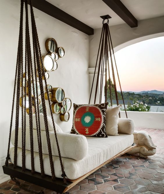 a hanging bed with white cushions and pillows on ropes looks very Mediterranean-like