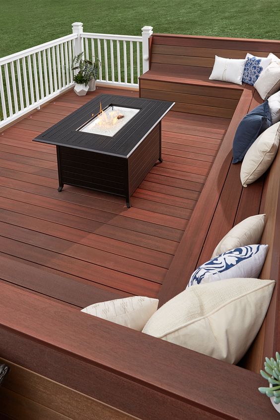 A laconic modern deck with a built in bench, a coffee table with a drink cooler in the center and sculptural planters