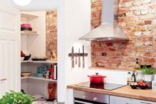 a modern farmhouse kitchen with white cabinets, shiny metal appliances and red brick walls