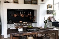 a modern farmhouse white kitchen with wooden beams on the ceiling, a vintage stained kitchen island and a matching stool