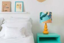 a modern tropical bedroom with a bed with yellow and white bedding, with a turquoise nightstand, a bright lamp and some woven touches to decor