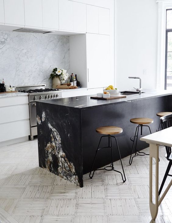a modern white kitchen and a black kitchen island, a marble backsplash and countertop to tie them up