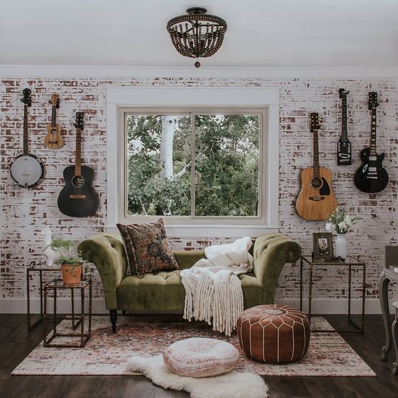 a music nook done with a whitewashed red brick wall and a refined green velvet sofa