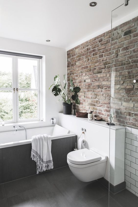 a neutral contemporary bathroom done with a single brick wall that adds character and style to the space
