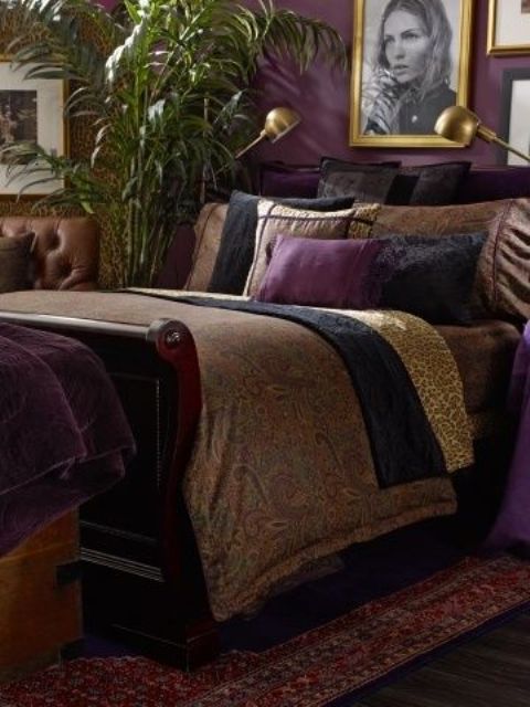 a refined and moody bedroom with purple walls, heavy dark furniture and a gallery wall in gold frames