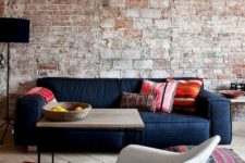 a rough brick wall with bricks of various sizes and colorfuul furniture and rugs to contrast