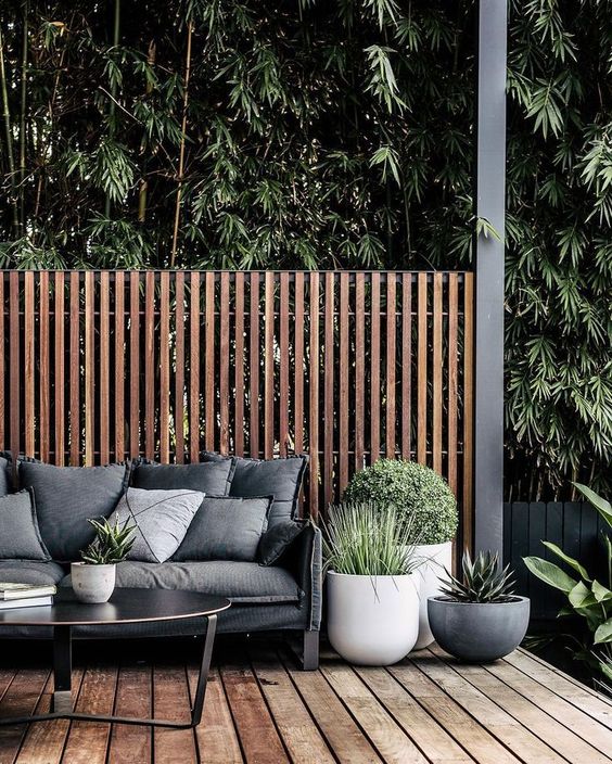 a small contemporary deck with dark stained furniture, potted greenery and succulents, a screen for privacy
