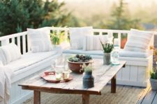 a small deck with a built-in white wooden bench, a rustic coffee table and a jute rug is very welcoming to receive guests