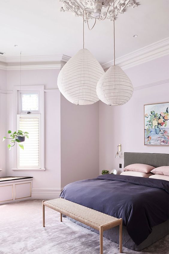 a stylish contemporary bedroom with blush walls, a grey bed, paper pendant lamps and pink and deep purple bedding