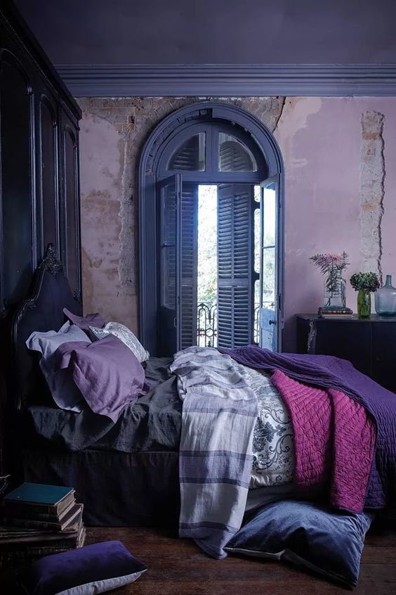 a unique bedroom with lavender walls, a deep purple bed and blue shutters, purple and pink bedding
