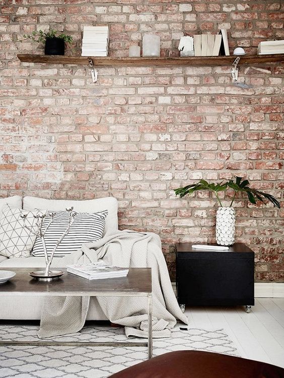 a welcoming living room with a muted red brick wall, neutral furniture and black touches