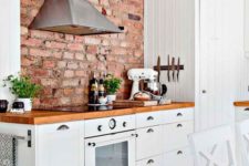 a welcoming modern farmhouse kitchen with white cabinets, rich stained countertops and a red brick wall