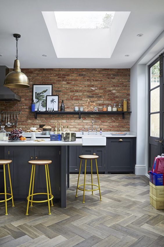 an eclectic kitchen with graphite grey cabinets, white countertops and red walls plus brass touches