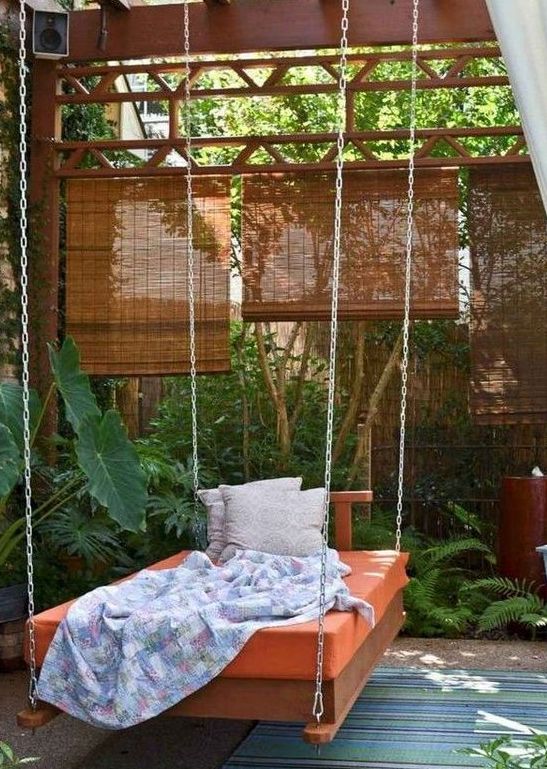 an outdoor hanging bed on chains with bright bedding, blankets and pillows is a fit for a tropical space